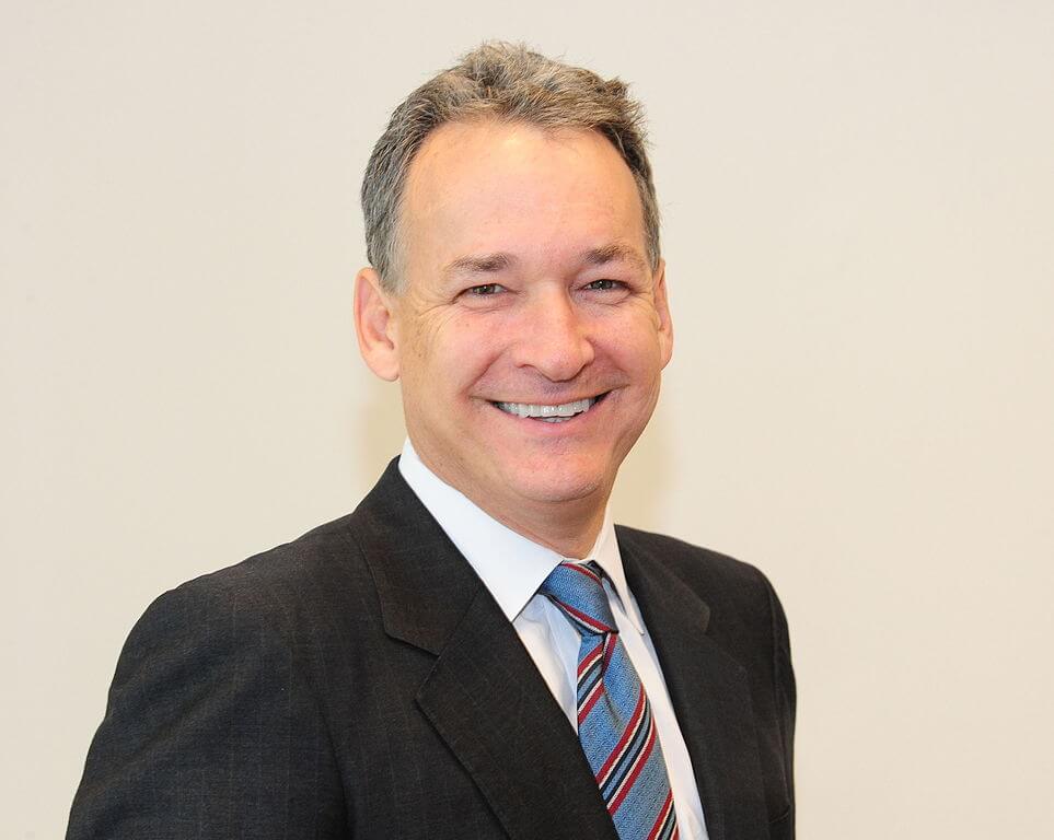 A headshot of a middle-aged Caucasian businessman with close-cropped blond/grey hair